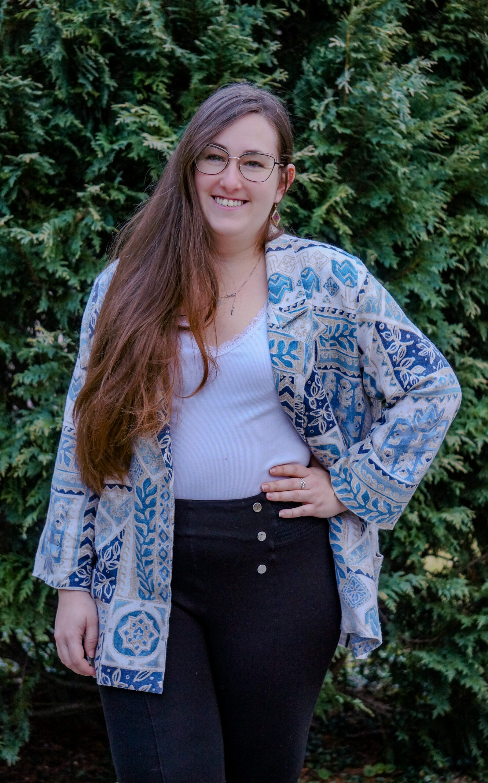 Professional portrait of Sara Arribas Colmenar. She's featuring long hair, a white shirt, and a blue and white blazer, with black pants.